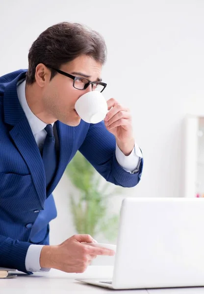 Jovem empresário bonito bebendo café no escritório — Fotografia de Stock