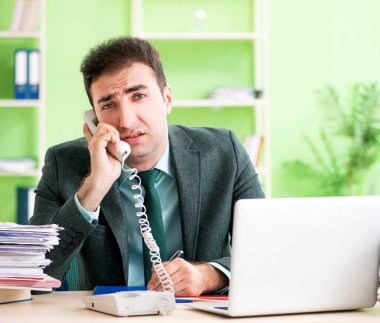 İşadamı ofiste otururken aşırı çalışmaktan kızgın.