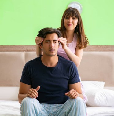 Yatak odasında kocasına masaj yapan bir kadın.