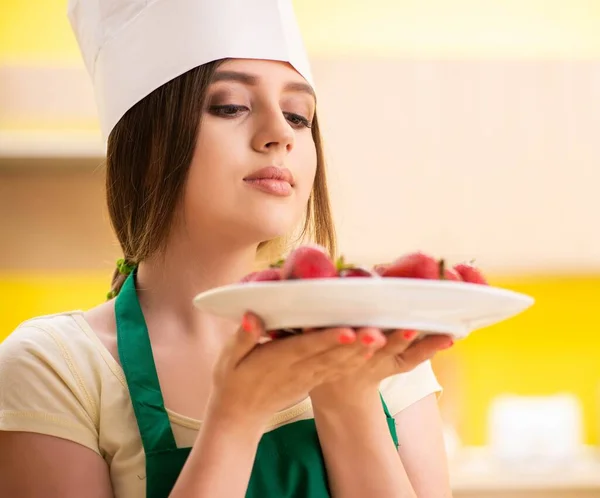 年轻的女厨师吃草莓 — 图库照片