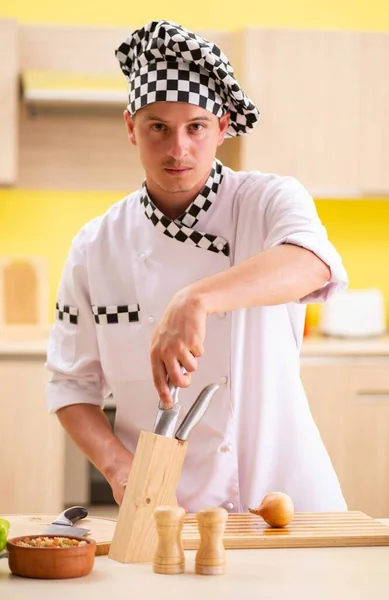 Joven cocinero profesional preparando ensalada en la cocina — Foto de Stock