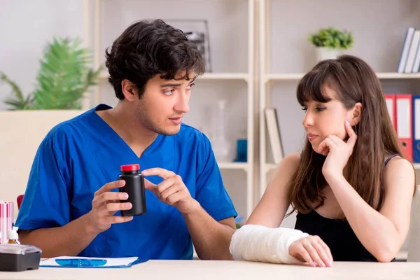 Young woman with bandaged arm visiting male doctor traumotologis — Stock Photo, Image