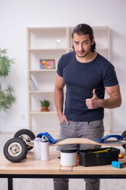 Kaykay tamir eden genç bir erkek tamirci.