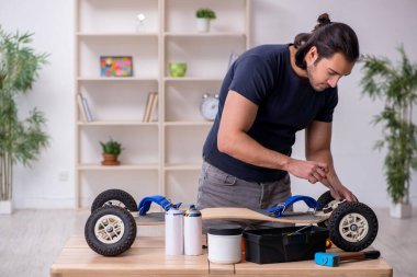 Kaykay tamir eden genç bir erkek tamirci.