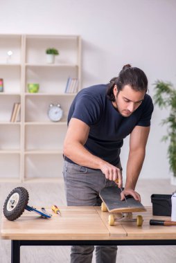 Kaykay tamir eden genç bir erkek tamirci.