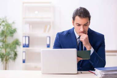 Genç adam ofiste pasaport kontrolü yapıyor.
