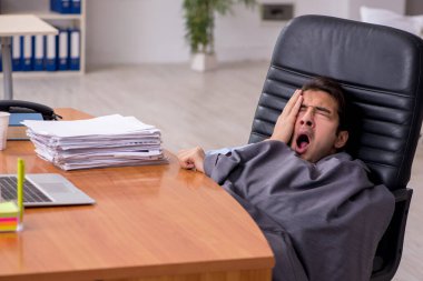 Genç erkek çalışan ofiste uyuyor.