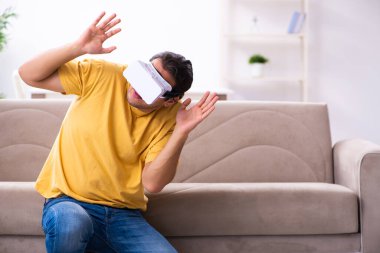 Evde sanal gerçeklik gözlüklü genç bir adam