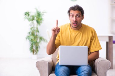 Evde bilgisayarı olan genç ve yakışıklı bir adam.