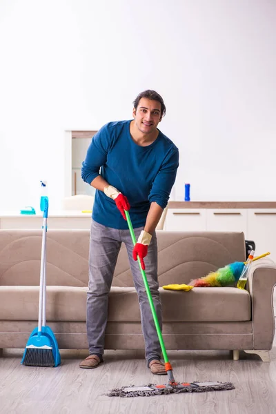 Jovem marido fazendo tarefas domésticas em casa — Fotografia de Stock