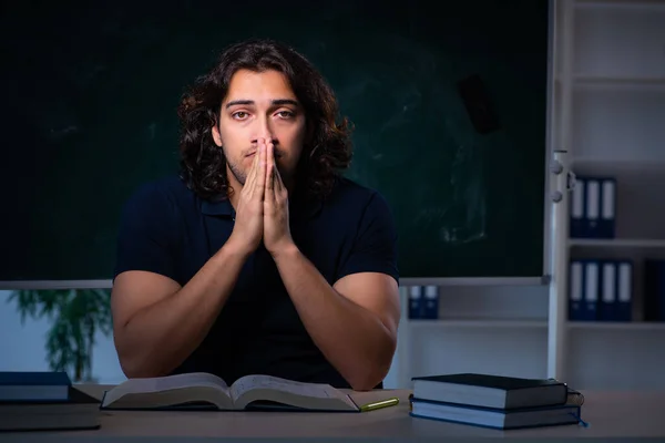 Joven estudiante masculino en el aula por la noche — Foto de Stock