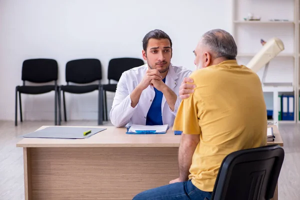 Velho paciente visitando jovem médico masculino — Fotografia de Stock