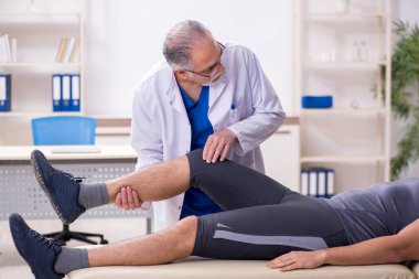 Genç erkek hasta yaşlı doktor travmatoloğu ziyaret ediyor.