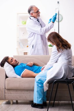 İki doktor hasta bir genci ziyaret ediyor.