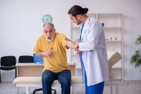 Velho homem ferido visitando jovem médico chiropractor — Fotografia de Stock