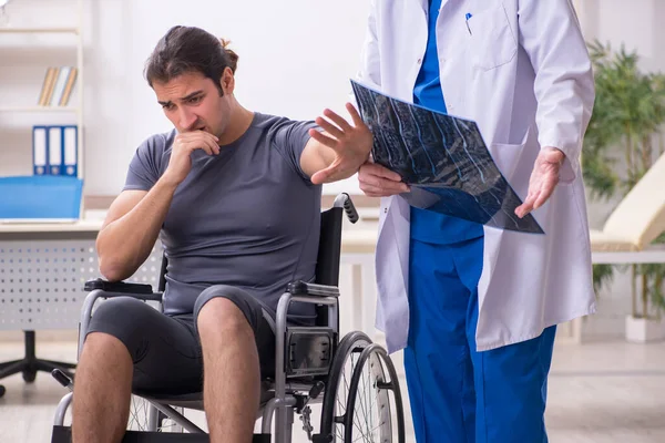 Joven paciente masculino en silla de ruedas visitando al viejo doctor radiologis —  Fotos de Stock