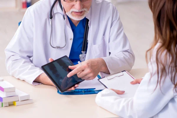 Gammal manlig läkare radiolog och hans unga kvinnliga assistent i th — Stockfoto