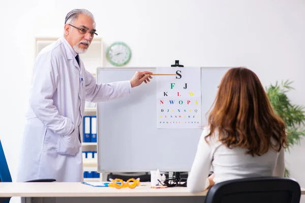 Jonge vrouw bezoekt oude mannelijke arts oogarts — Stockfoto