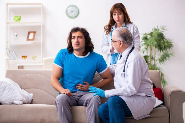 Twee dokters op bezoek bij zieke jongeman thuis — Stockfoto