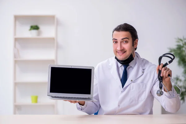 Jovem médico do sexo masculino com estetoscópio reparar computador — Fotografia de Stock