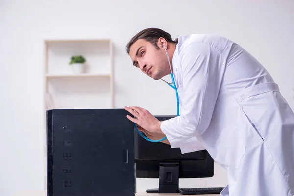 Giovane medico di sesso maschile con stetoscopio riparazione computer — Foto Stock