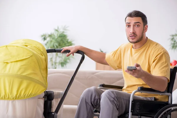 Jongeman aannemer in rolstoel op zoek naar pasgeborene — Stockfoto