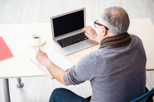 Gammal manlig anställd som arbetar hemifrån under en pandemi — Stockfoto