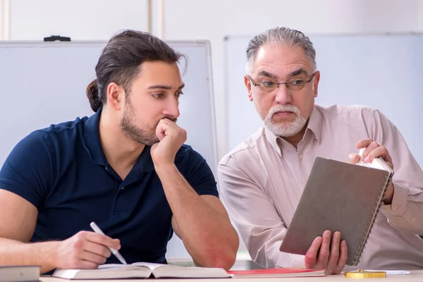 Old teacher and young male student in the classroom — Stock Photo, Image