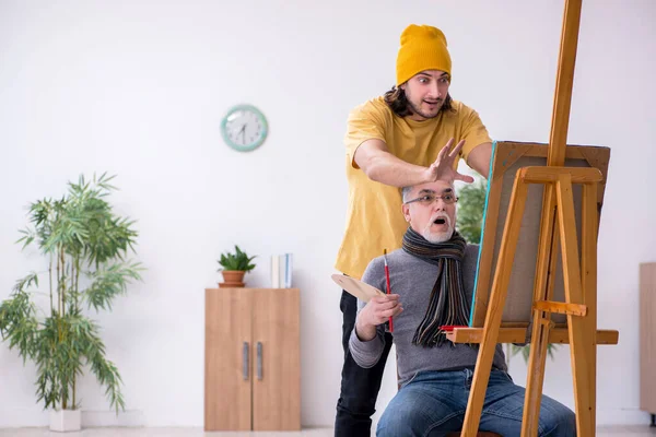 Old man taking lesson from young painter — Stock Photo, Image