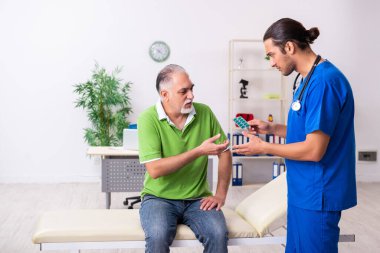 Yaşlı adam genç erkek gastroenteroloğu ziyaret ediyor.