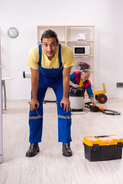 Due appaltatori che riparano il frigorifero in officina — Foto Stock