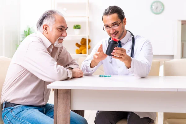 Joven médico varón visitando a paciente viejo en casa — Foto de Stock