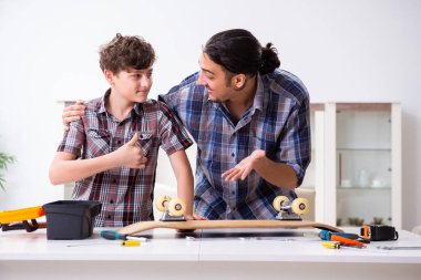 Genç baba oğluyla kaykay tamir ediyor.