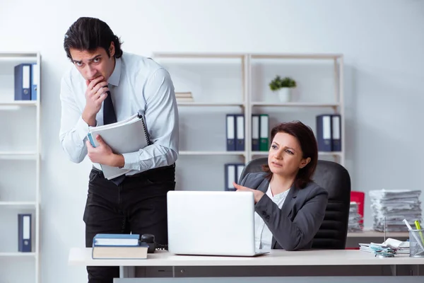 Old female boss and young male employee in the office