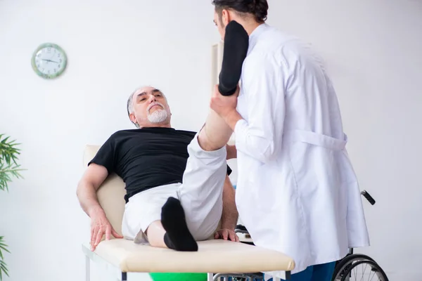 Vecchio ferito visitando giovane medico — Foto Stock