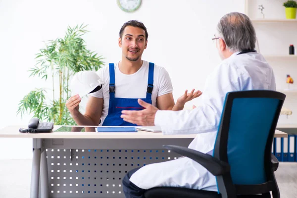 Genç erkek müteahhit yaşlı doktoru ziyaret ediyor.