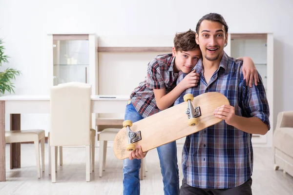 Young father repairing skateboard with his son at home — Stock Photo, Image