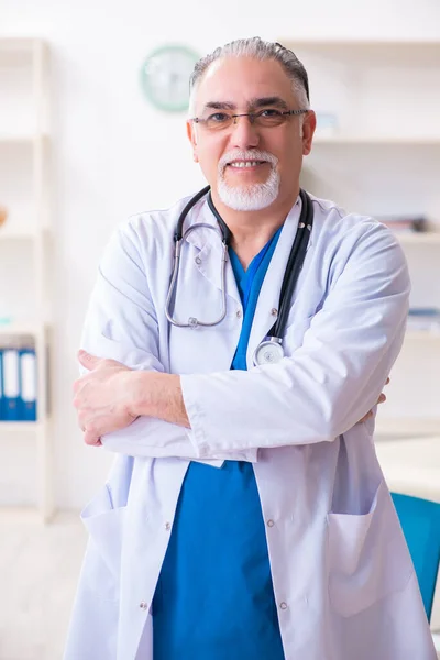 Oude mannelijke arts werkzaam in de kliniek — Stockfoto