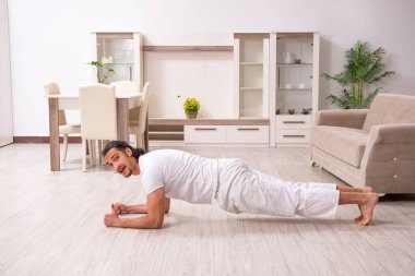 Genç adam evde fiziksel egzersiz yapıyor.