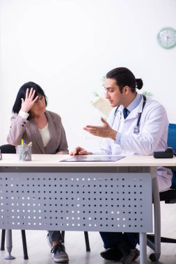 Genç doktor yaşlı yaşlı kadını muayene ediyor.