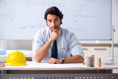 Genç erkek mimar beyaz tahtanın önünde.