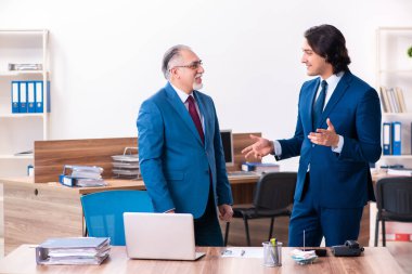 Genç ve yaşlı çalışanlar ofiste birlikte çalışıyorlar.