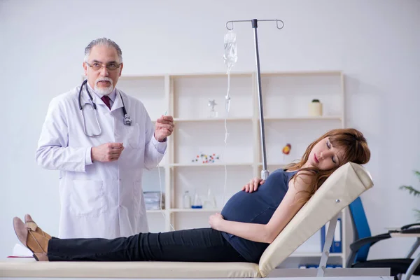 Velho médico examinando jovem mulher — Fotografia de Stock