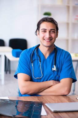 Genç erkek doktor röntgen görüntülerine bakıyor.
