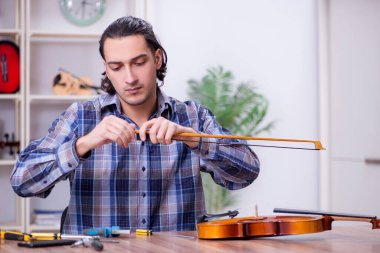 Kemanı tamir eden yakışıklı bir tamirci.