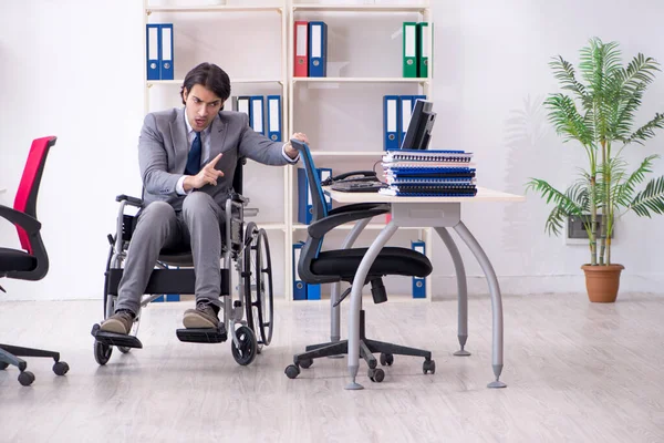Nuori komea työntekijä pyörätuolissa työskentelee toimistossa — kuvapankkivalokuva