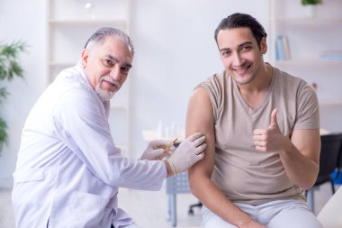 Erkek hasta aşı aşısı için doktoru ziyaret ediyor.