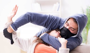 Silahlı bir adam evde genç bir kadına saldırıyor.