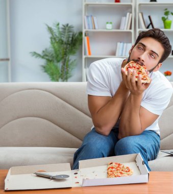 Pizza yiyen adam evde yemek yiyor, dinleniyor.