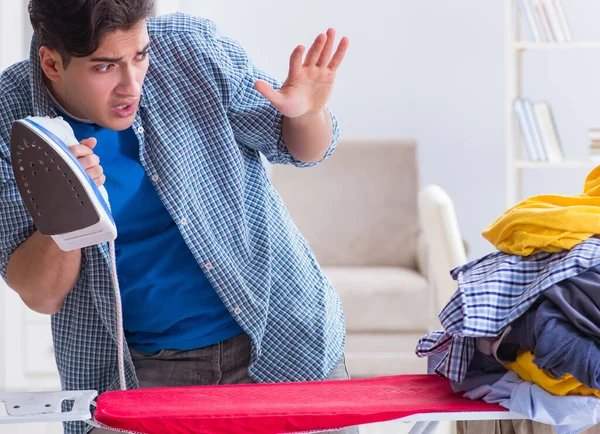 Ung man make gör kläder strykning hemma — Stockfoto